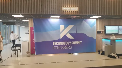 Stor bakvegg med logo og fjellmotiv på en scene i Kongsberg.